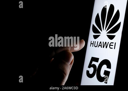 Huawei 5G Logo auf einem Bildschirm des Smartphones in einem dunklen Raum und einen Finger zu berühren. Stockfoto