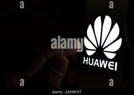 Huawei Logo auf einem Bildschirm des Smartphones in einem dunklen Raum und einen Finger zu berühren. Stockfoto