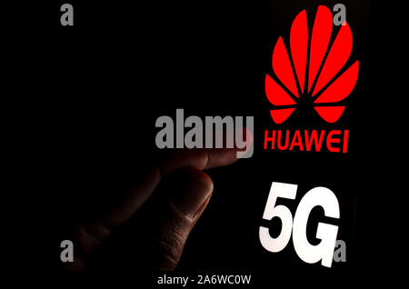 Huawei 5G Logo auf einem Bildschirm des Smartphones in einem dunklen Raum und einen Finger zu berühren. Stockfoto
