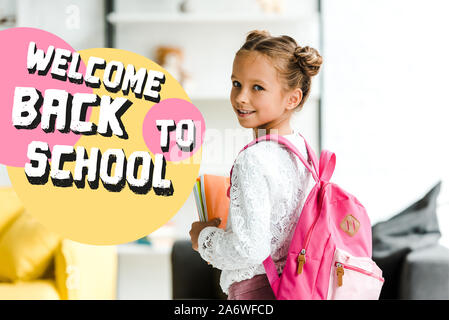 Lächelnd Schulkind holding Bücher beim Stehen mit Rucksack in der Nähe willkommen zurück Schule Briefe an Stockfoto