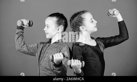 Glückliche Kinder Trainer mit Barbell. Fitness Ernährung für Energie Gesundheit. Training von kleinen Mädchen halten Hantel. Gewicht heben für muscules. Kindheit Aktivität. Sport Erfolg. Planung Zeit mit Trainer. Stockfoto