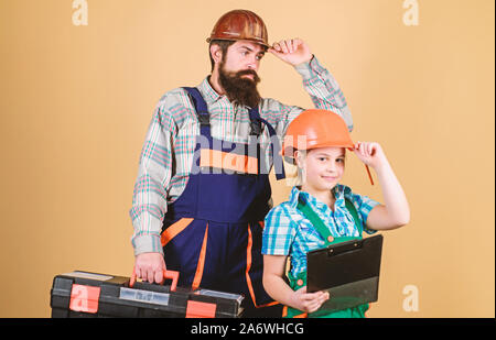 Vater und Tochter in der Werkstatt. Bärtiger Mann mit kleines Mädchen. Bauarbeiter assistant. Builder oder Tischler. Handwerker in Uniform. Ingenieur. Reparieren. Kinder Kreativität. Team bei der Arbeit. Stockfoto