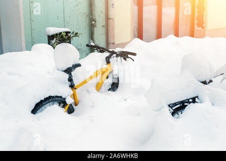 Fahrrad mit großen dicken Schneeschicht nach Blizzard auf der europäischen Stadt Straße im Winter abgedeckt. Abgebrochene Fahrrad im Schneesturm in der Nähe von Gebäude begraben im Freien Stockfoto