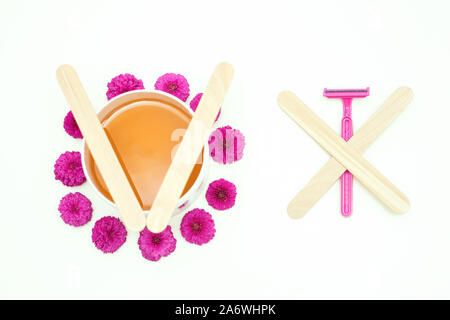 Flach, oben Glas mit Wachs mit rosa Blumen vs Rasiermesser für Haarentfernung auf weißem Hintergrund. Konzept der Depilation Stockfoto