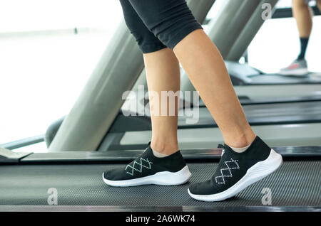Schließen bis Fuß sneakers Fitness Mädchen läuft auf Track Laufband, Frau mit muskulösen Beine in Gym Stockfoto