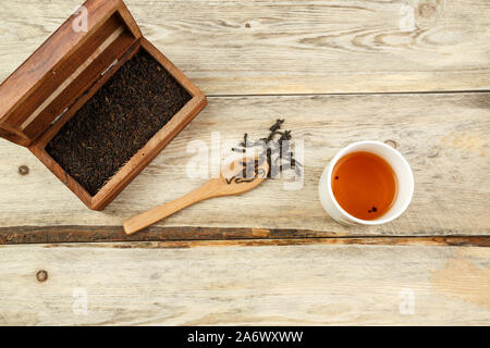 Schwarz indischen Tee in einer Box, auf einen Löffel und in einem Glas auf einem hölzernen Hintergrund gebraut. Der Blick von oben Stockfoto