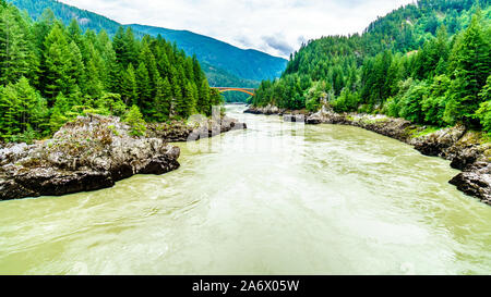 Die mächtigen Fraser River, mit der die bogenförmigen Stahlkonstruktion des Alexandra Brücke auf dem Trans Canada Highway in der Ferne in BC, Kanada Stockfoto