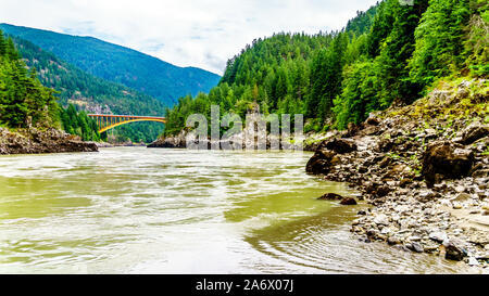 Die mächtigen Fraser River, mit der die bogenförmigen Stahlkonstruktion des Alexandra Brücke auf dem Trans Canada Highway in der Ferne in BC, Kanada Stockfoto