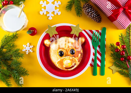 Das kreative Weihnachten Kind essen Kunst essbare Hirsche auf rote Platte mit Sterne statt Hörner als xmas Frühstück. Art, niedliche Rehe aus Pfannkuchen und Beeren. Stockfoto