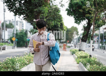 Asiatische student Blick auf Watch in Eile Stockfoto