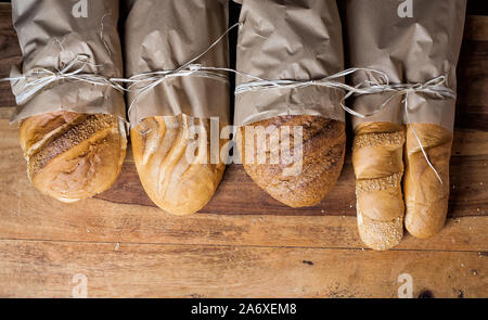 Andere Art von Brot in Papiertüten gestrickt mit einem Seil auf dem Holztisch. Stockfoto