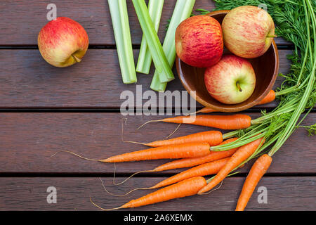 Gemüse und Obst. Bündel von Karotten und Äpfel in eine Schüssel auf dem Holz. Stockfoto