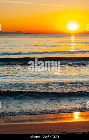 Den Sonnenuntergang Sonne hinter dem Horizont. Tyrrhenische Meer Bucht mit Insel Elba auf dem Hintergrund auf den Sonnenuntergang. Cala Violina Strand, Scarlino, Pr Stockfoto