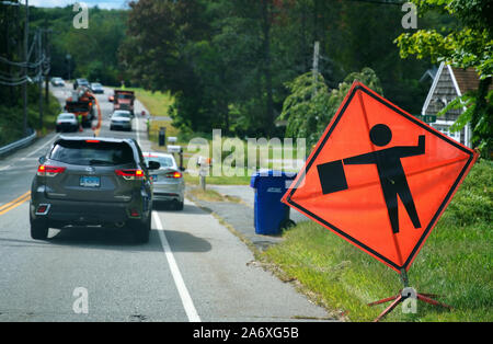 Storrs, CT USA. 16.September 2019. Flagman orange Warnschild Warnung Fahrer während der Winter Baumschnitt Operationen zu verlangsamen. Stockfoto