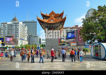 Menschen tanzen traditionelle Musik am Memorial Gate des Jinbi Platzes, Stadt Kunming, Provinz Yunnan (China) Stockfoto