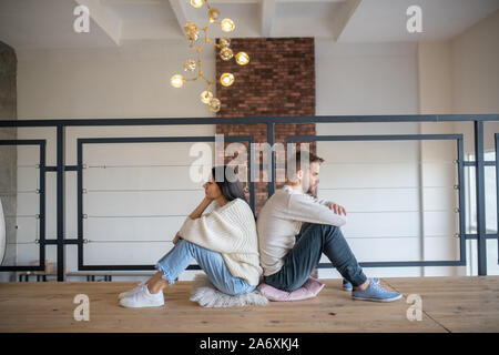 Mann und Frau Rücken an Rücken sitzen nach dem Argument Stockfoto