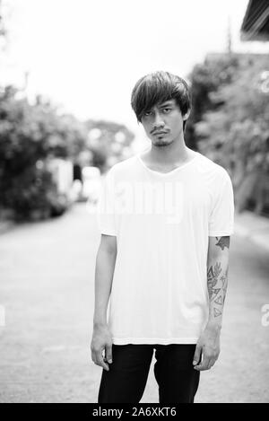 Jungen asiatischen Menschen mit Tätowierungen im Freien in Schwarz und Weiß Stockfoto