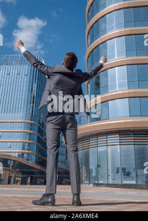 Ansicht der Rückseite. happy Geschäftsmann stand vor der hohen Bürogebäudes. Stockfoto