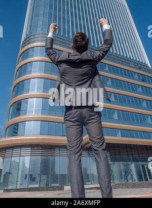 Ansicht der Rückseite. happy Geschäftsmann stand vor der hohen Bürogebäudes. Stockfoto