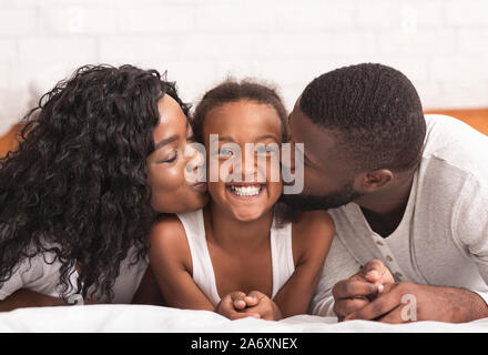 Liebende schwarze Eltern küssen Wangen Ihrer glücklichen kleinen Tochter Stockfoto