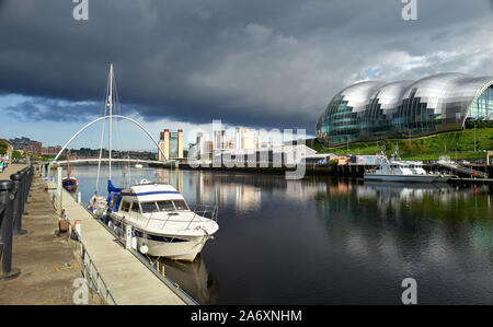 Eine Yacht günstig bei Newcastle Quayside mit den Baltischen Kunst Museum, Salbei und Gateshead Millennium Bridge in der Ferne. Stockfoto