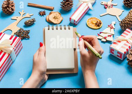 Blick von oben auf die weibliche Hand einige Tasten an noteebok auf blauem Hintergrund. Neues Jahr Dekorationen und Spielzeug. Weihnachten Konzept. Stockfoto