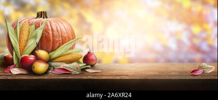 Ein Thanksgiving Feier Tabelle der Kürbisse, Äpfel, Birnen und Maiskolben mit Herbst Sonnenuntergang Laub im Hintergrund. Stockfoto