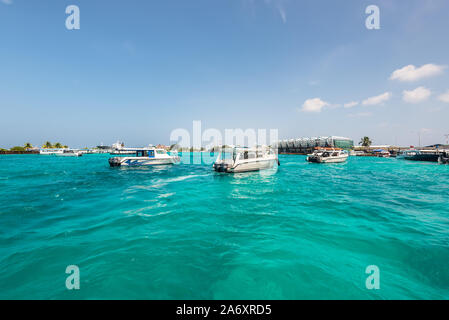 Hulhule Island, Malediven - November 18, 2017: Speed Boote segeln auf den Pier am internationalen Flughafen Ibrahim Nasir, Malediven, Indischer Ozean. Turquoi Stockfoto