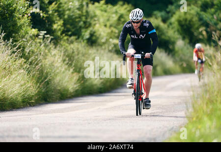 ROTHBURY, NEWCASTLE UPON TYNE, England, UK - Juli 06, 2019: ein Radfahrer Feilbietenden an einem Feldweg an der Zyklon Rennen von Newcastle nach Northu Stockfoto