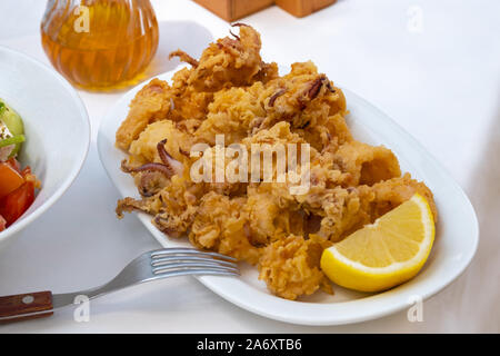 Frittierter Tintenfisch und Gabel auf weißen Tischdecke Stockfoto