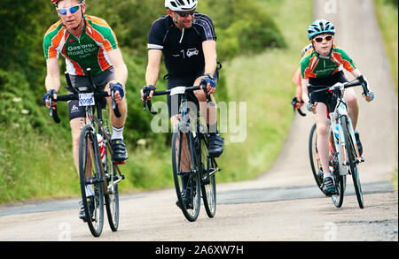 ROTHBURY, NEWCASTLE UPON TYNE, England, UK - Juli 06, 2019: Jung und Alt Radfahrer arbeiten hart Reiten auf einem Hügel an der Zyklon Rennen von Newcas Stockfoto