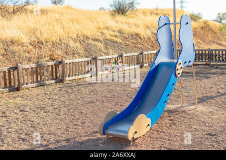 Metallic- und Holz- Folie mit anderen schwingt in einen Kinderspielplatz mit Kies und Holz- Fechten für die Sicherheit von Kindern Stockfoto