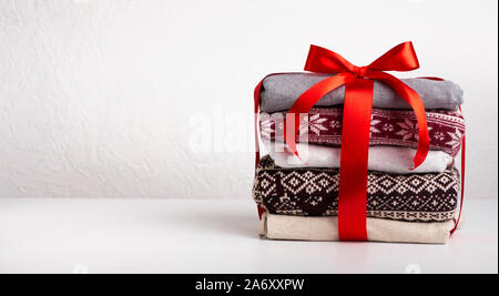 Stapel Pullover von Red Ribbon gewickelt mit Bogen auf Weiß Stockfoto