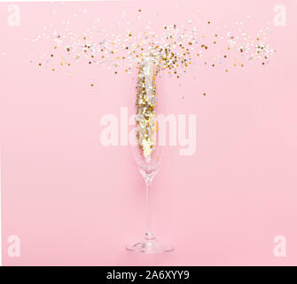 Kreative minimalistisch Foto Champagner Glas mit gold Konfetti auf Rosa Stockfoto