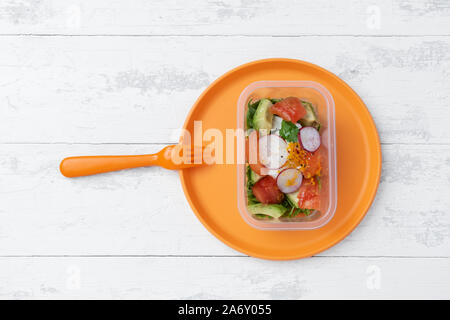 Salat in einer Plastikbox auf einer Platte Stockfoto