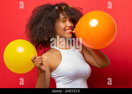 Mädchen mit schwarzen lockigen Haar entfaltet zwei Ballons Stockfoto