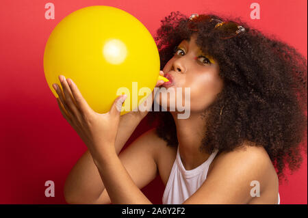 Modell mit einem üppigen Frisur einen Ballon aufbläst Stockfoto