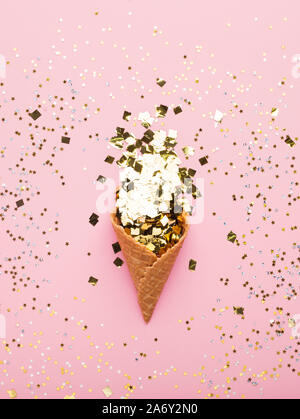 Waffel horn voll Gold Konfetti auf rosa Hintergrund Stockfoto