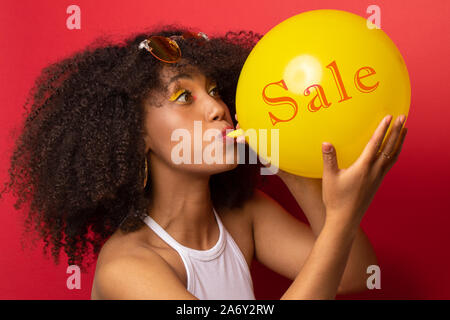 Mädchen bläst die Kugel mit der Aufschrift Umsatz Stockfoto