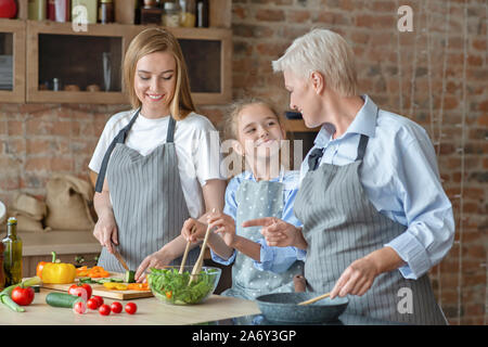 Süße Mädchen glücklich Mama und Oma mit Abendessen helfen Stockfoto