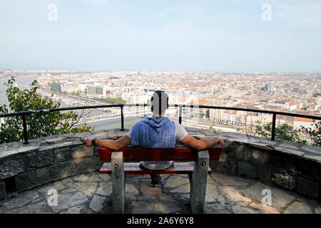 Mann von hinten sitzen auf einer Bank und genießen den Blick über Budapest, Ungarn Stockfoto