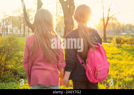 Silhouetten der beiden Kind Mädchen zu Fuß im Park halten sich an den Händen, während Sonnenuntergang Stockfoto