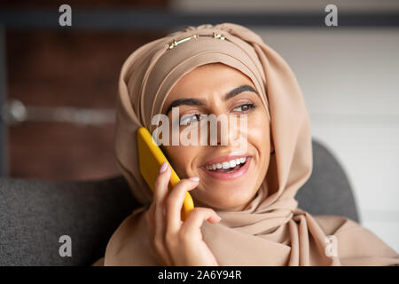 Lächelnd muslimischen Mädchen, am Telefon zu sprechen mit Freund Stockfoto