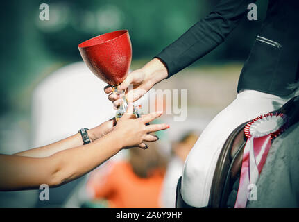 Feierliche Verleihung des roten Tasse der Reiter - der Gewinner der Pferdesportwettbewerbe, und der Rosa Rosette hat bereits zu dem Pferd ausgezeichnet. Stockfoto