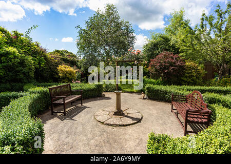 Ruhe und Frieden, Bänke und Sonnenuhr in der Geheimen Memorial Garden, Great Torrington, Devon, Großbritannien. Stockfoto