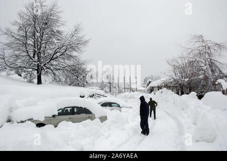 Nicht erkennbare Mann Reinigung der Schnee vor einem Auto, im Schnee bedeckt. Personen und Fahrzeug bilden. Reinigung Schnee, Schneefall im Winter Stockfoto