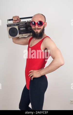Ein Mann mit einem lustigen Schnurrbart in Sonnenbrille auf weißem Hintergrund posiert. Party im Retro-Stil, die Idee für das Kostüm. Stockfoto