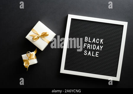 Schwarzer Freitag verkauf Konzept. Schreiben board mit Schild "Black Friday sale", Geschenkboxen über schwarzen Hintergrund. Flach, Ansicht von oben, Overhead. Stockfoto