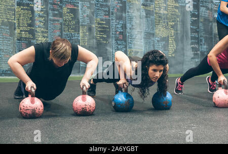 Sportlerinnen, Push-ups mit den Kettlebells Stockfoto