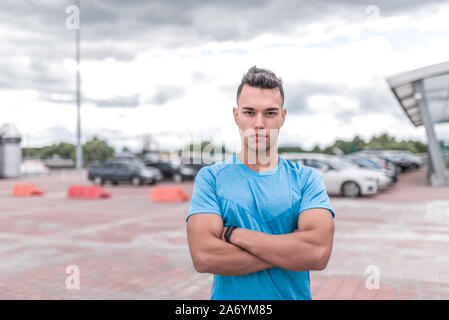 Sportliche Mann steht selbstbewusst, Trainer stellt, mutige Blick Selbstsicher und stark, Ausbildung in der Stadt im Sommer, ein aktiver Lebensstil, moderne Stockfoto